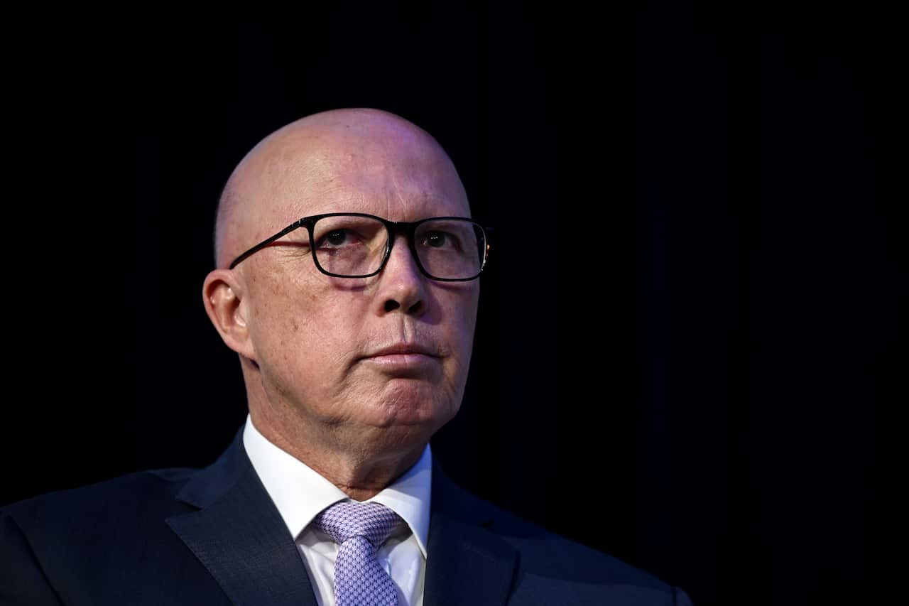 A man wearing a suit and glasses against a black background