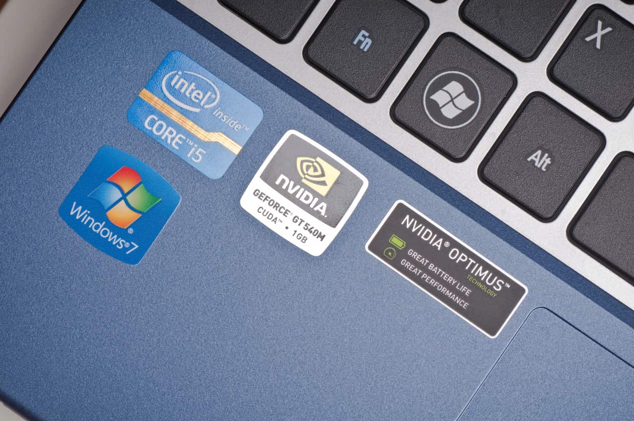 A small portion of a laptop keyboard with Microsoft, Intel and Nvidia stickers on it.