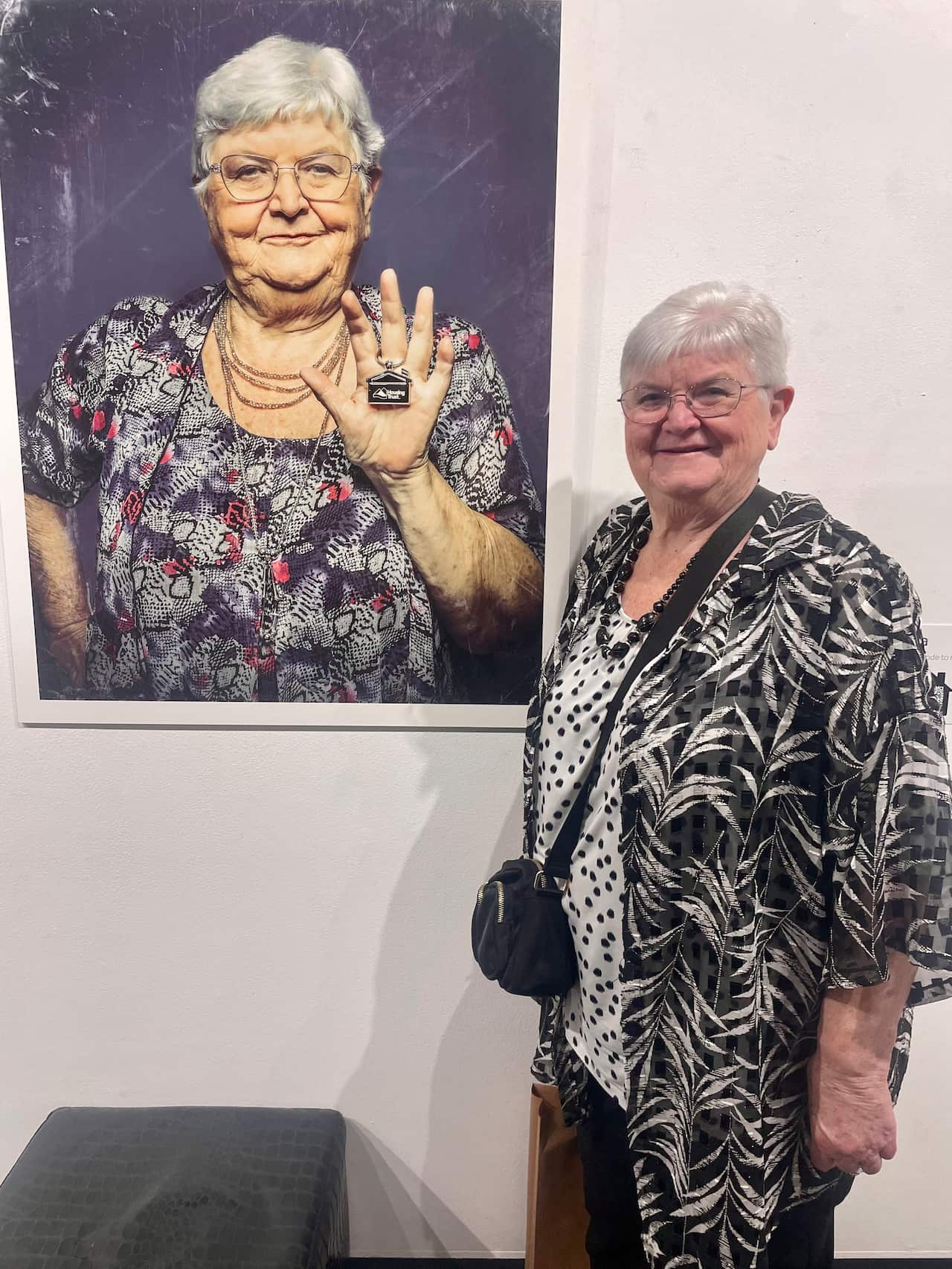 A woman standing in front of a painting of herself.