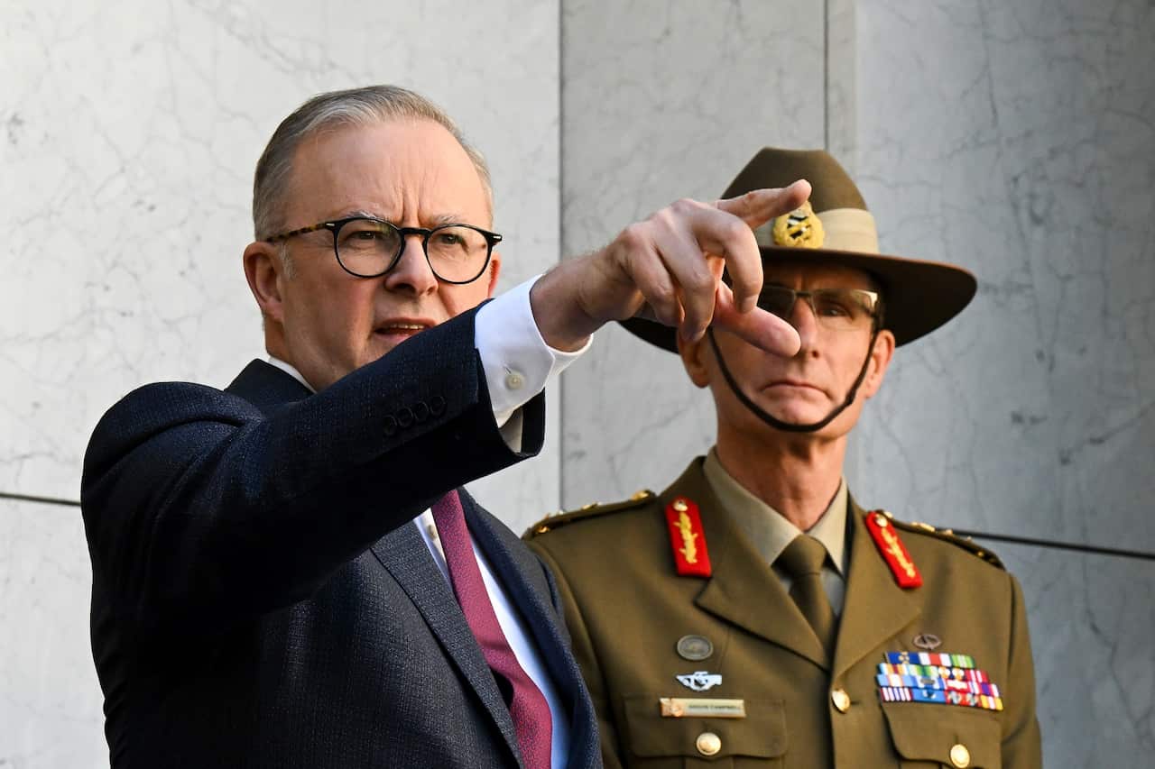 Australian Prime Minister Anthony Albanese points into the distance as he stands next to Australian Defence Force Chief Angus Campbell.