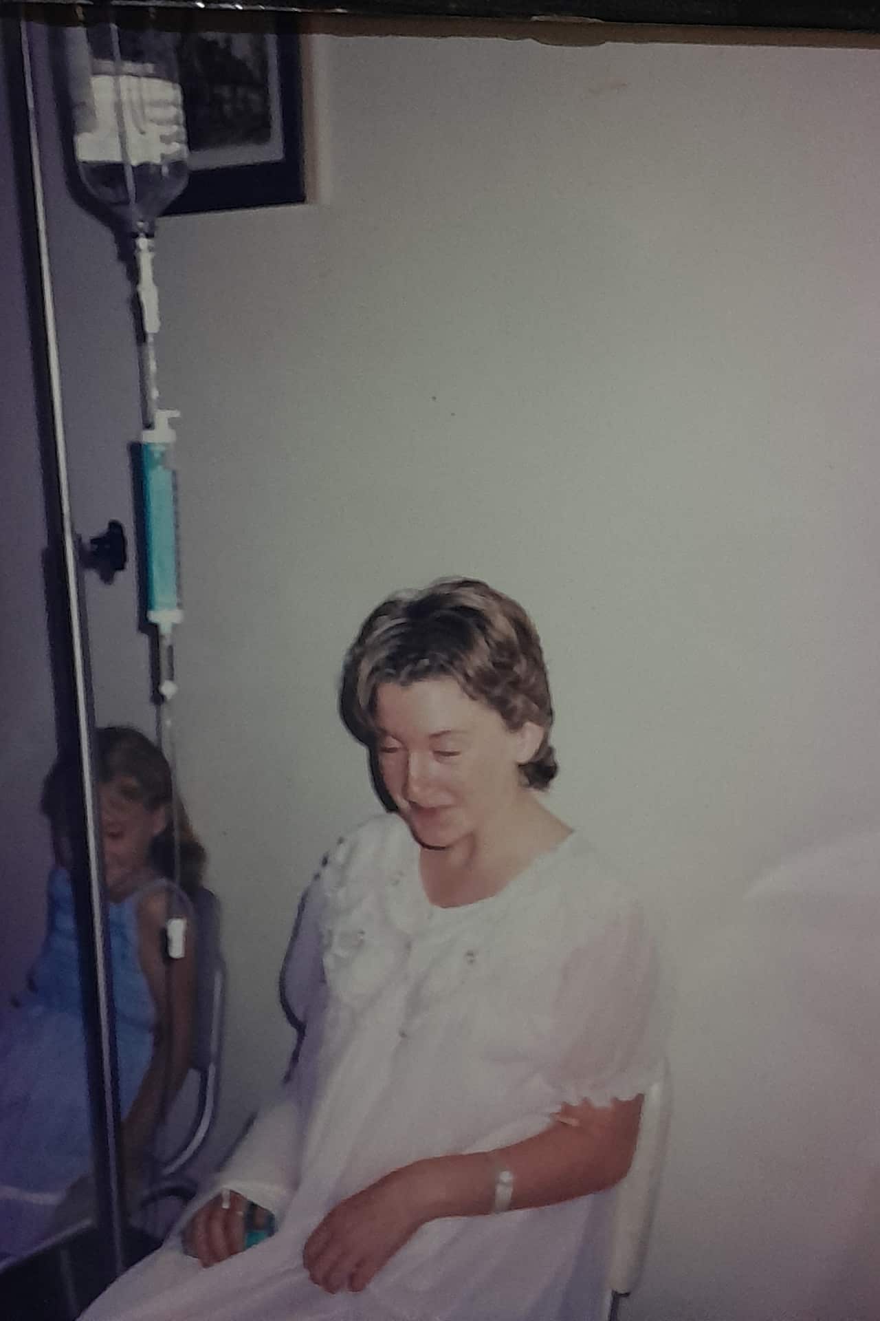 a young woman in a hospital gown holding onto an IV