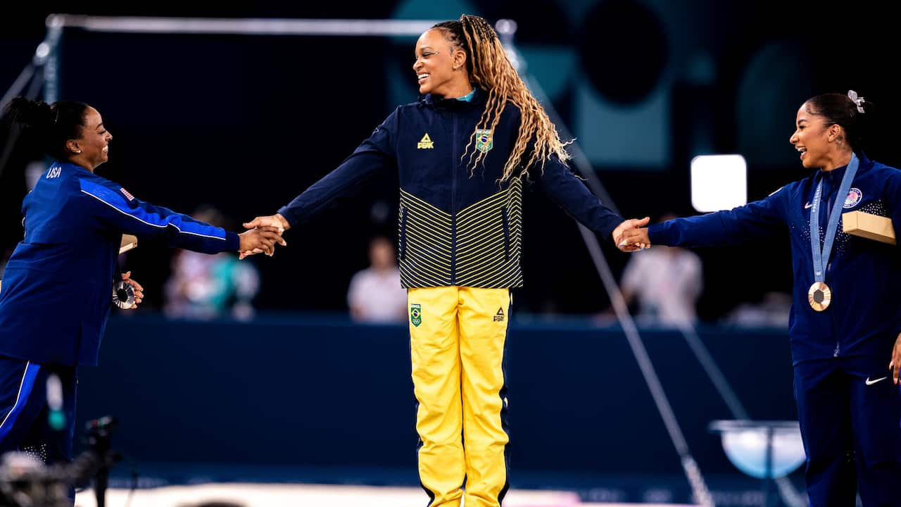 Three women on a podium hold hands