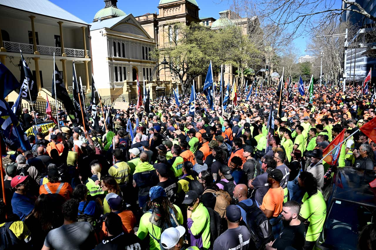 A large group of protesters, many in hi-vis, standing out the front of a building.