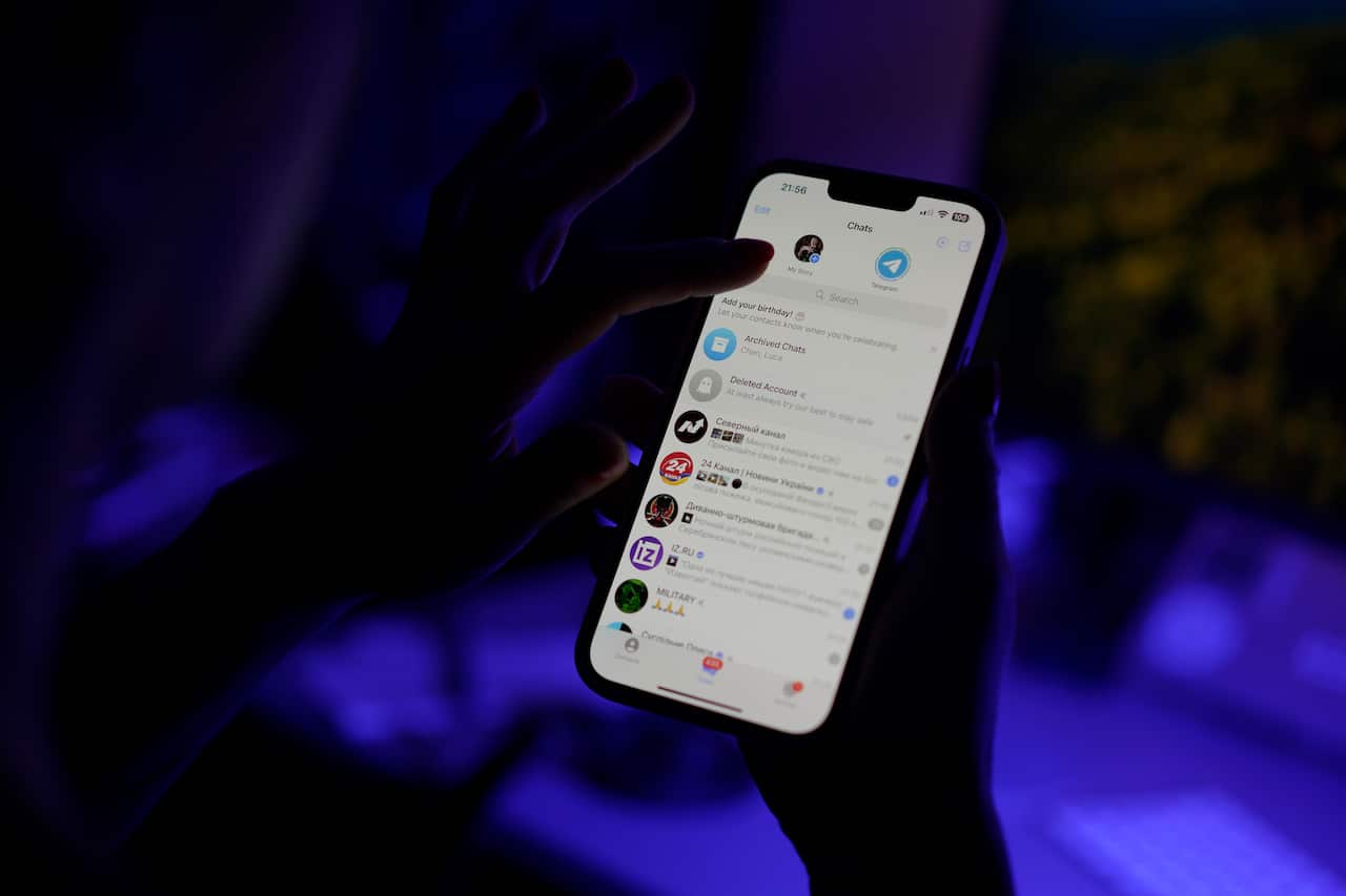 A hand holding a phone that is open to the Telegram messaging app.