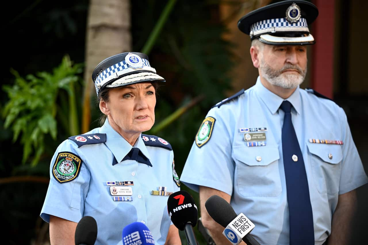 A man and a woman wearing police uniform address the media. 