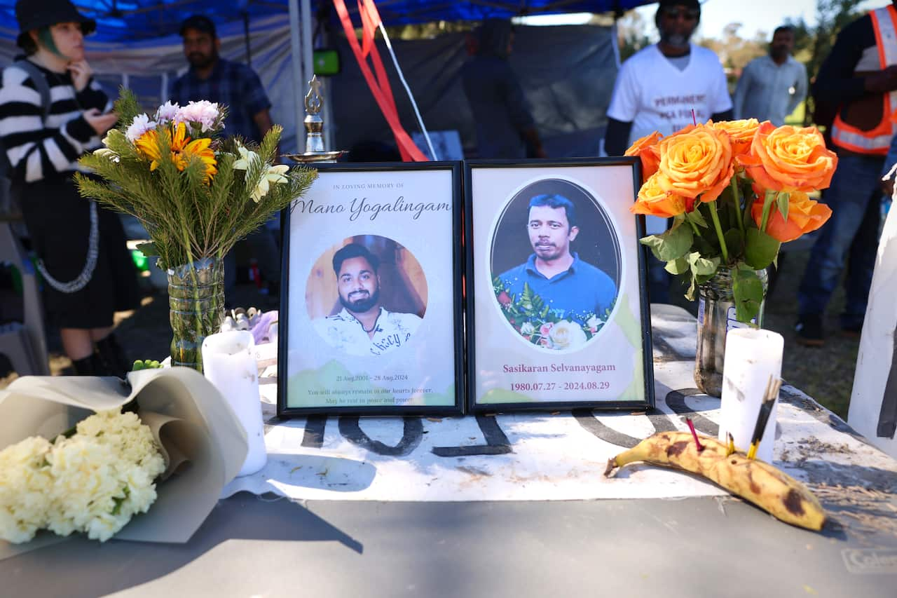 A small shrine outside featuring framed photographs of two men, a candle, a banana and flowers