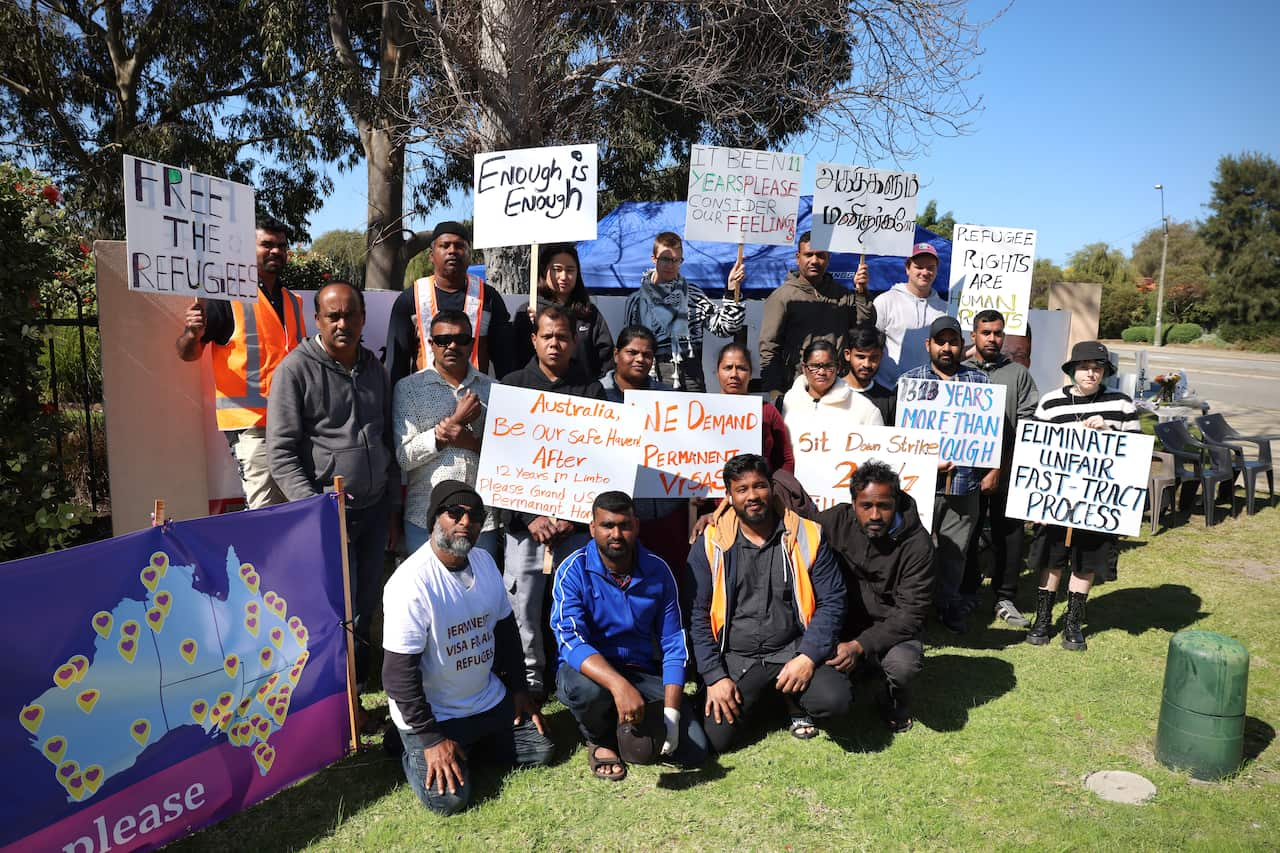 Around 20 protesters outside. Many are holding signs calling for permanent residency.