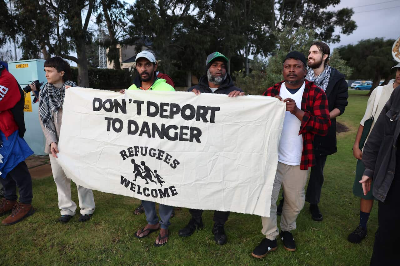 Refugees protesting at a Perth encampment event holding up a sign that reads Don't deport to danger Refugees welcome 