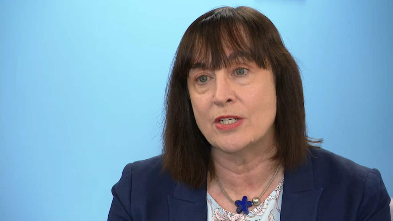 A woman speaking in front of a blue background