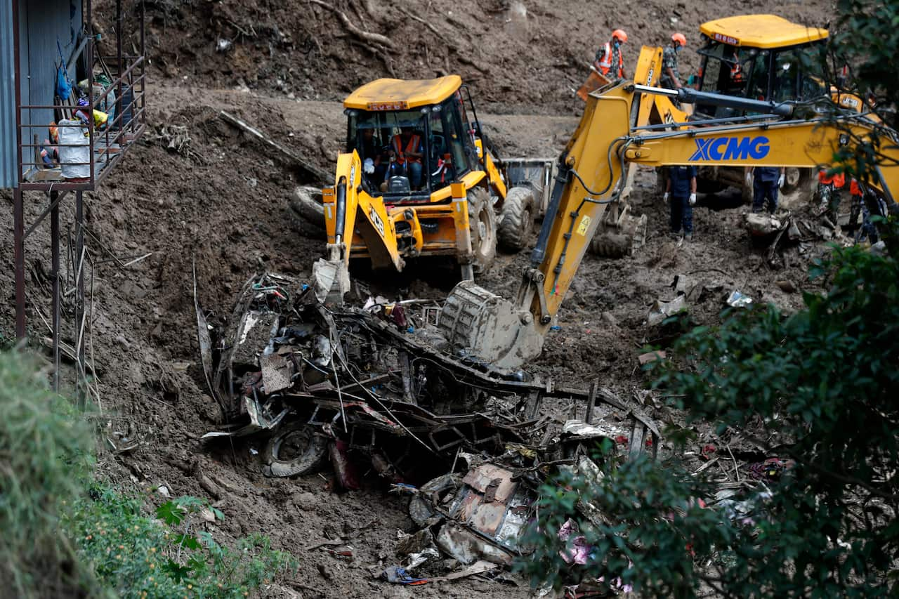 Digger removing car debris from landslide.