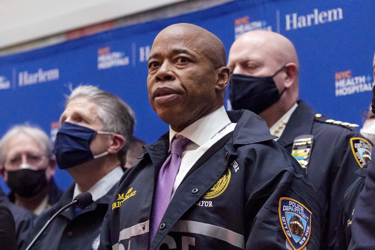 A man in uniform speaking next to officials in face masks.