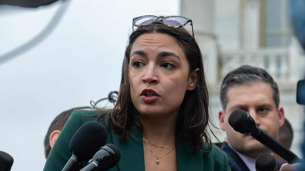 A woman speaking into several black microphones being held up near her.