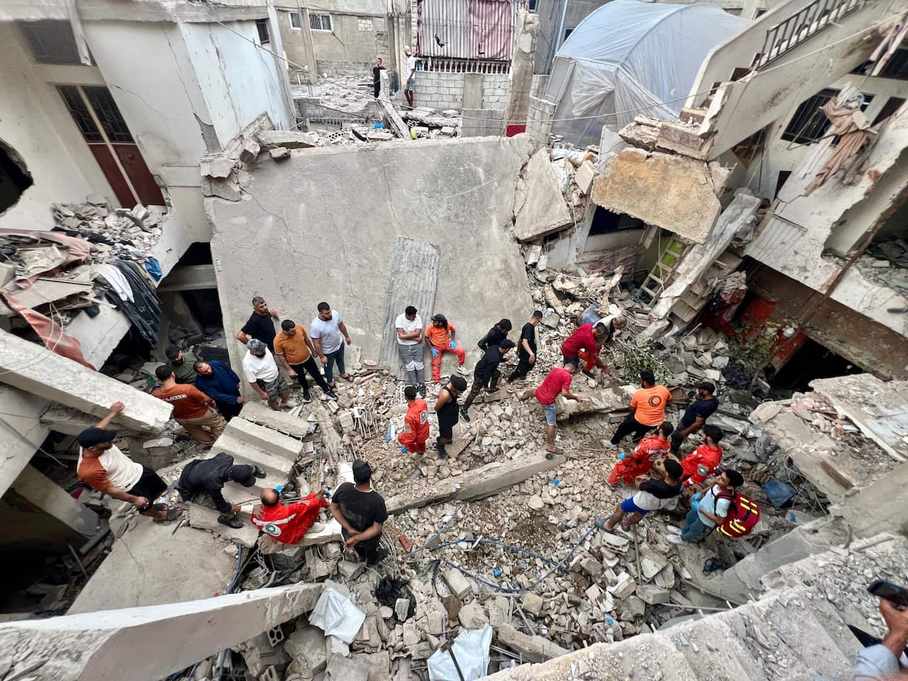 A group of people searching through the rubble of a damaged building.