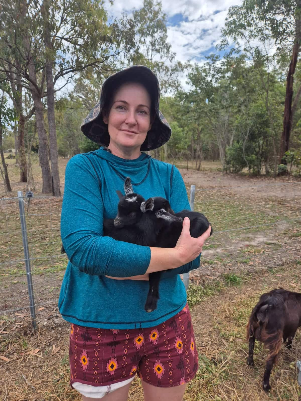 a woman holding a baby goat