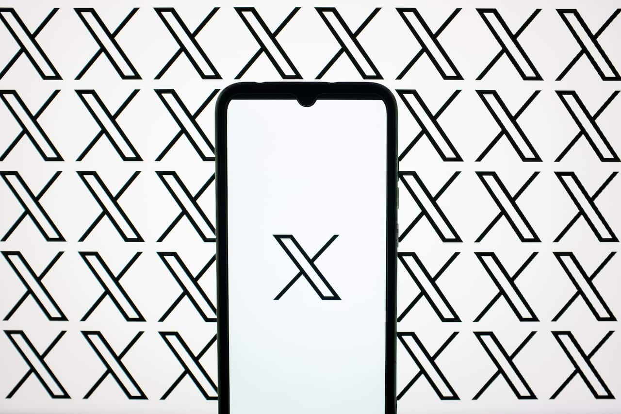 A graphic illustration of a phone screen with the 'X' logo set in front of 'X's in the background.