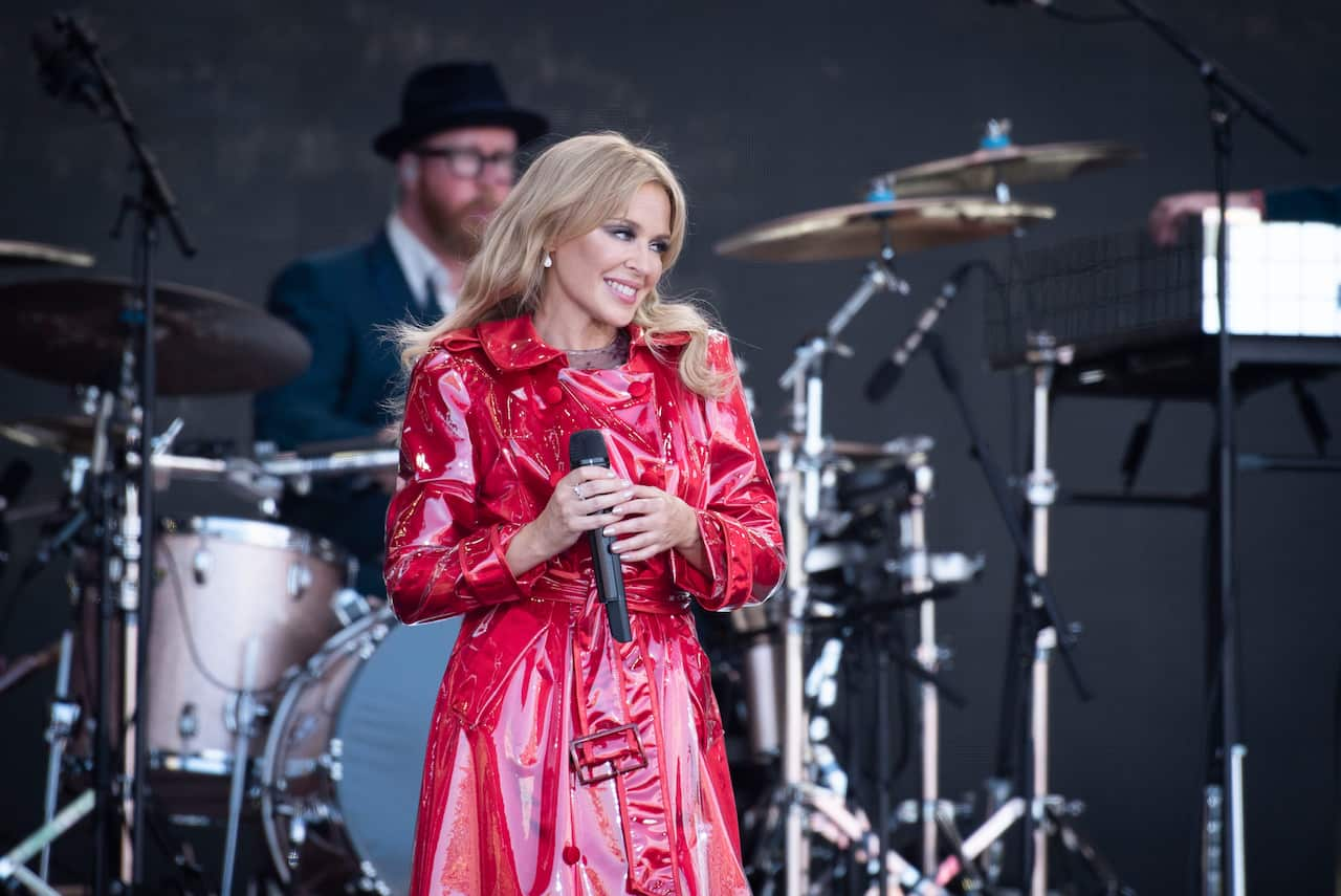 A woman in a red PVC coat performs on stage.