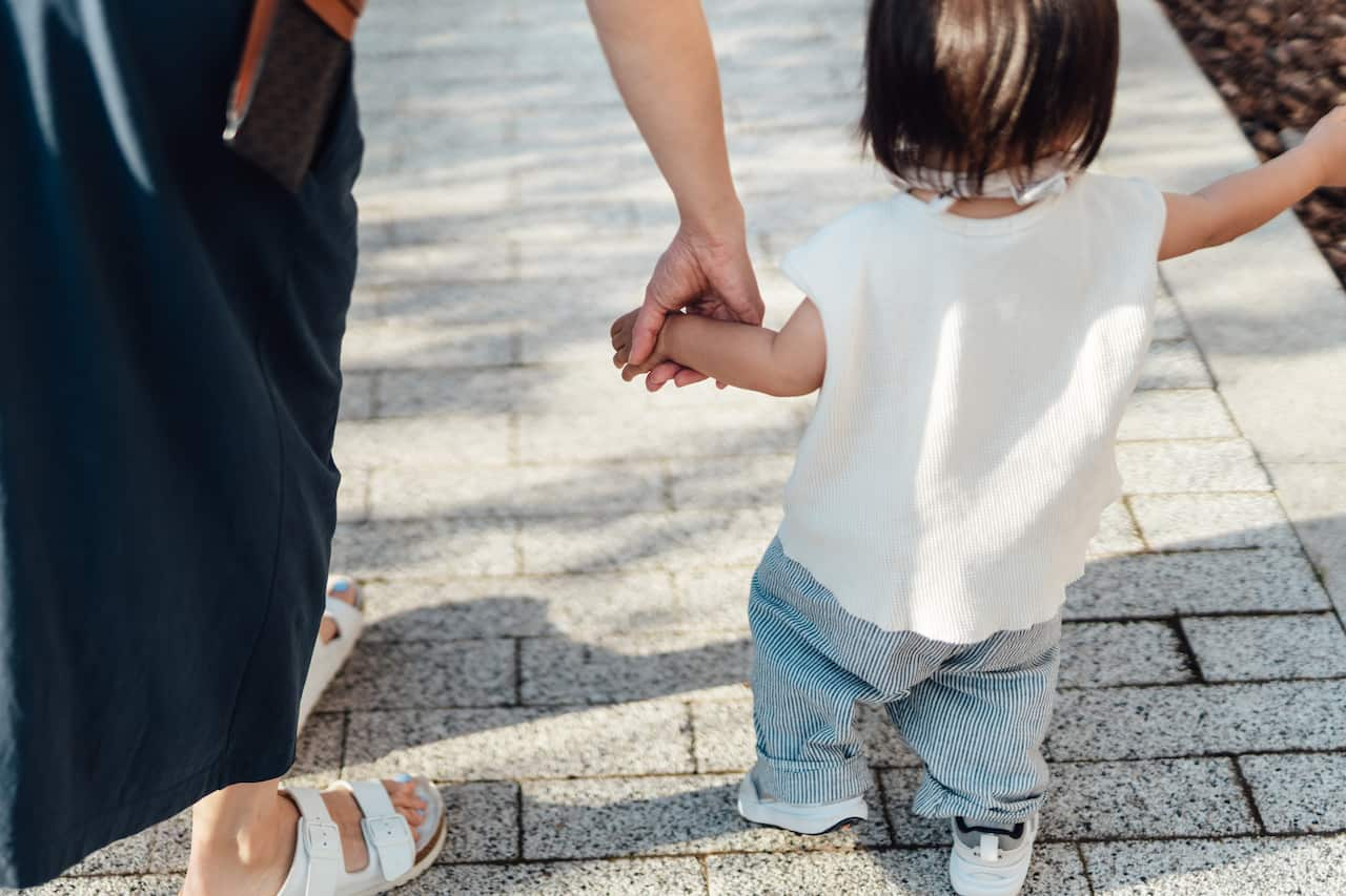 toddler and mother holding hands walking