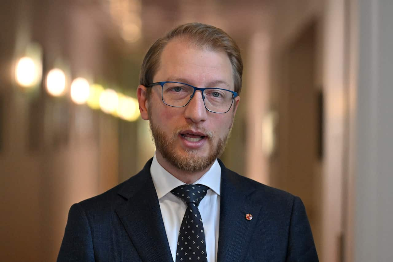 Close up of a politician with blue glasses, wearing a suit.