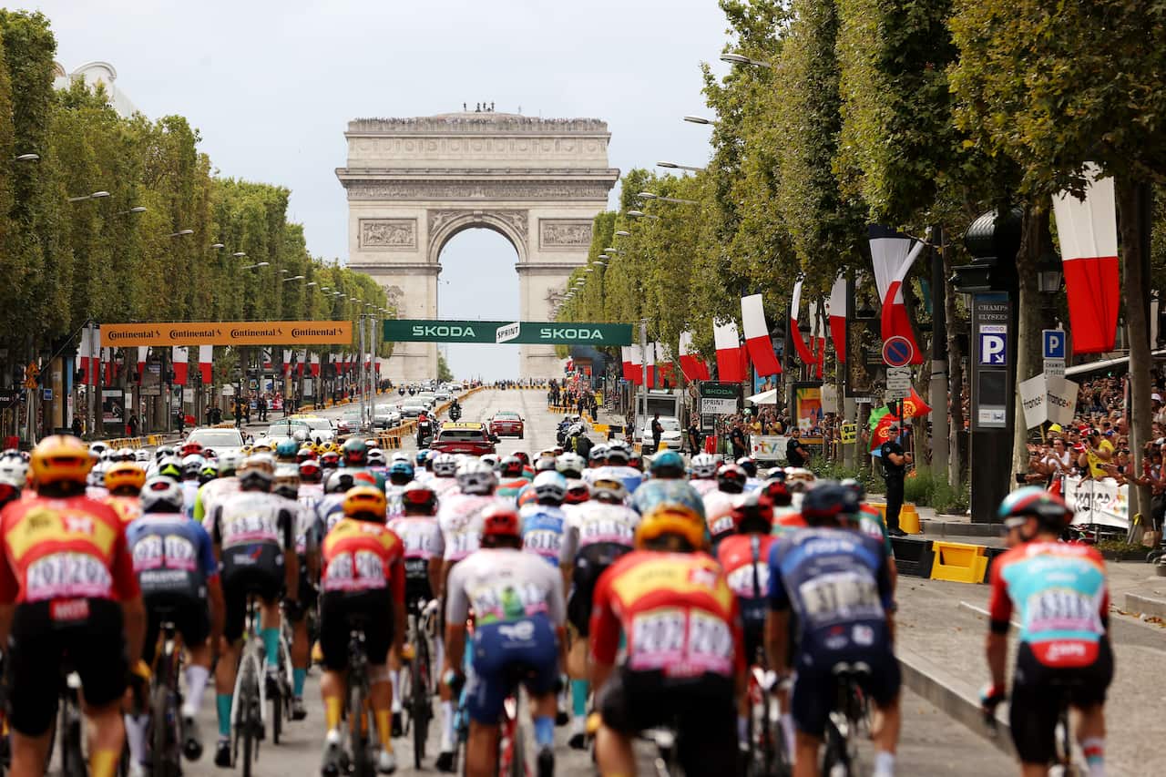A pack of cyclists heads towards the Arc de Triomphe in Paris.
