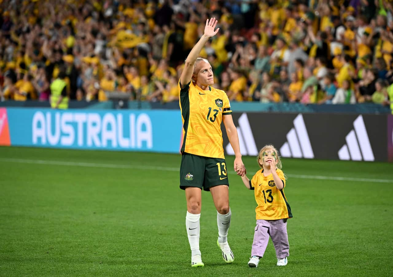 A woman and young girl in yellow football shirts walking on grass