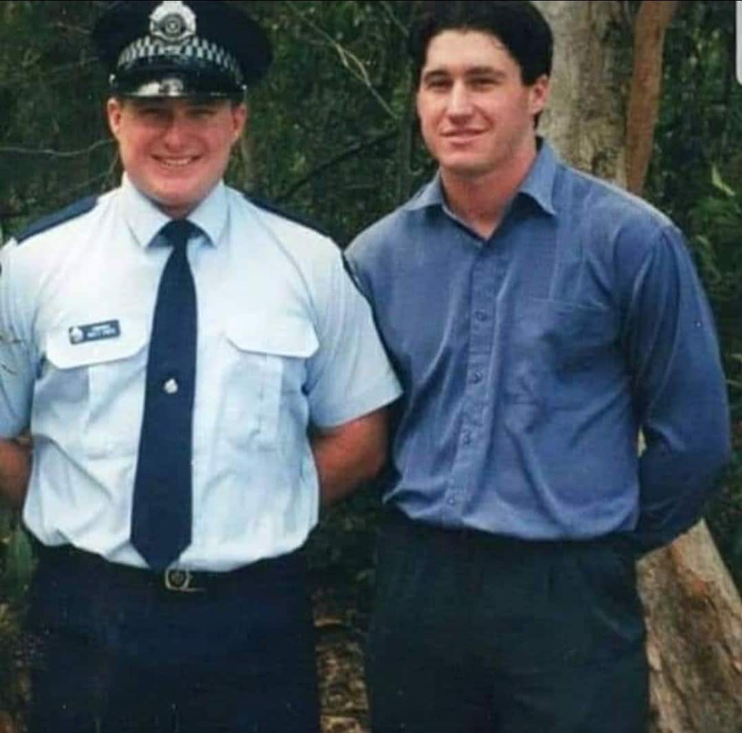 A police officer standing next to a man in a blue shirt