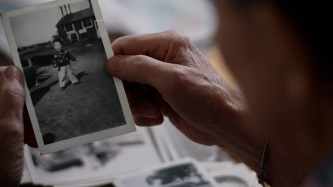 Hands holding a black and white photograph of a small child