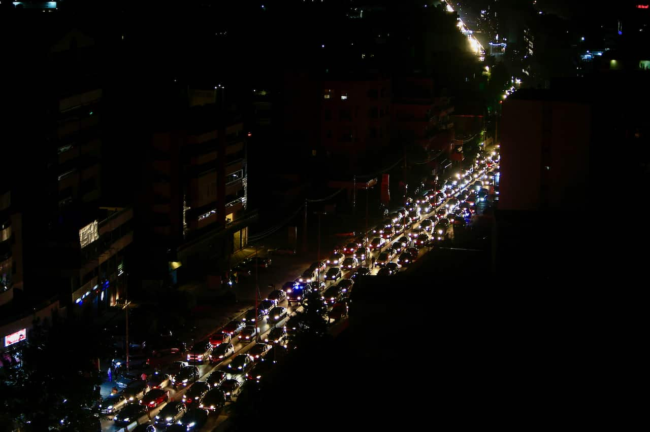 A long line of cars backed up on a road with their headlights on.