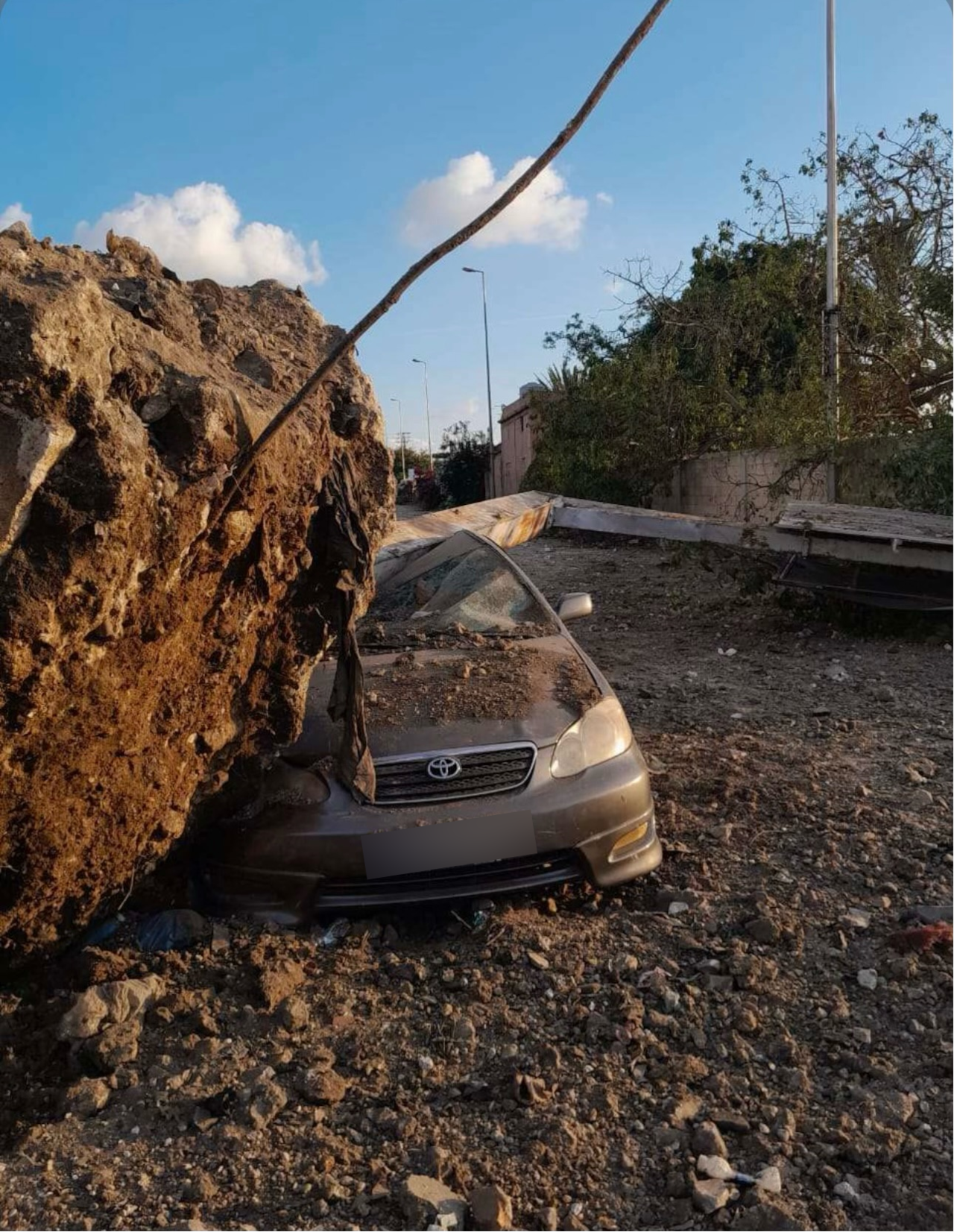 A car is slammed underneath a huge rock.