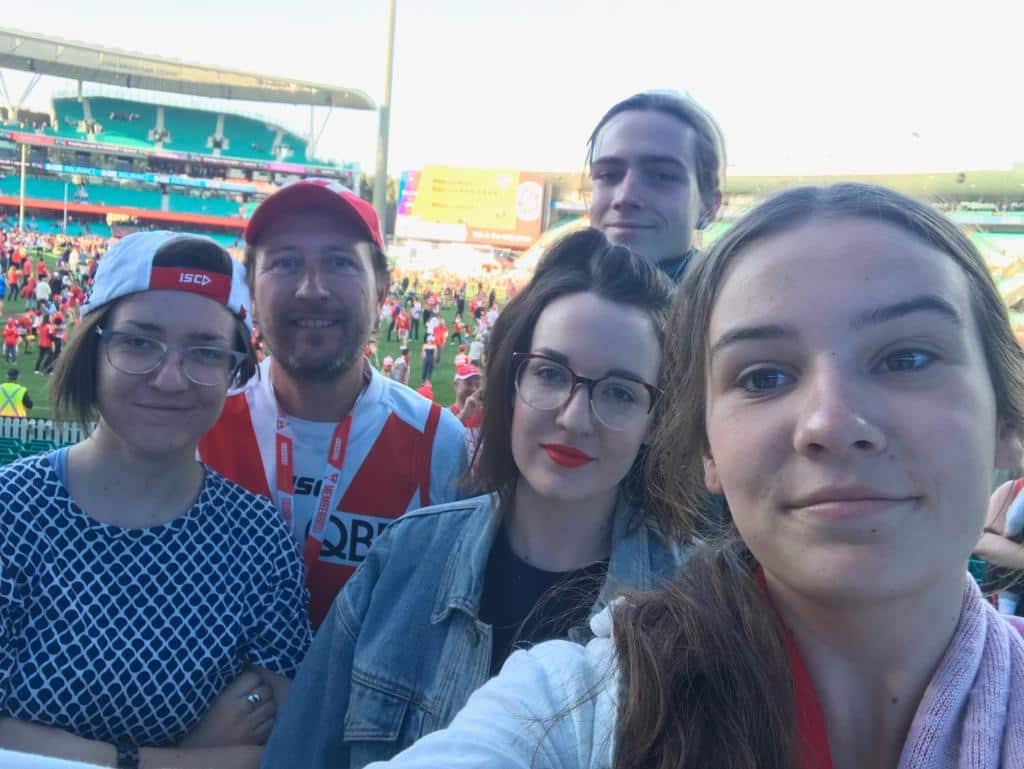 Five people smiling standing on a football pitch