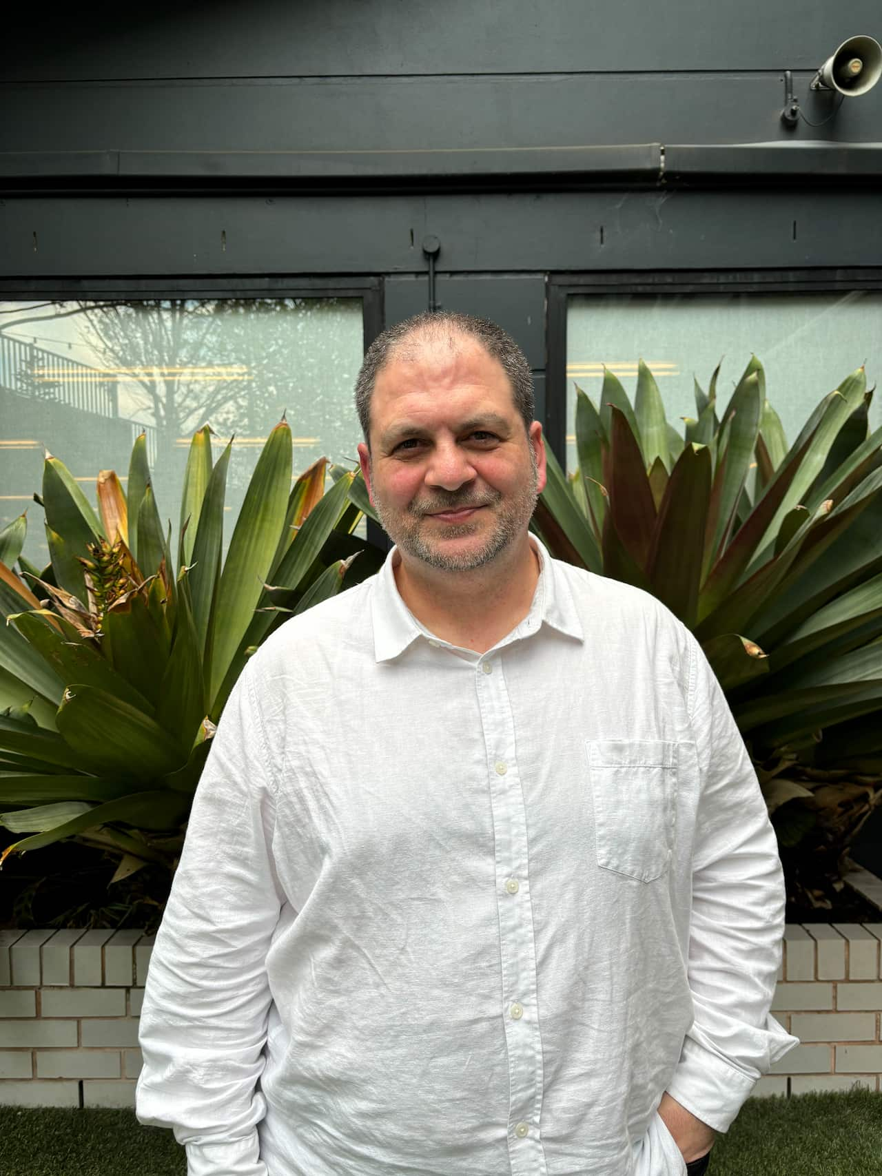 A man in a white shirt smiles at the camera.