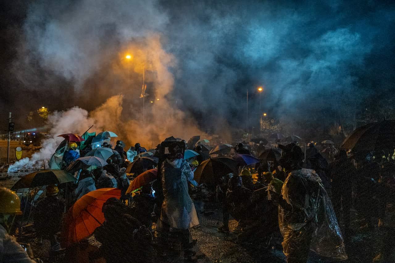 Protesters stand inside a cloud of tear gas smoke. 