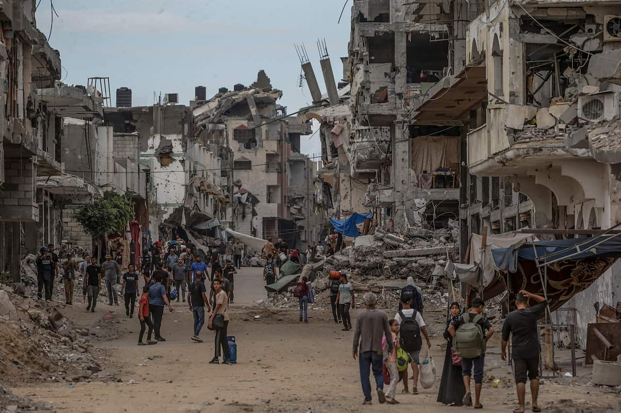 People walk through a city in ruin