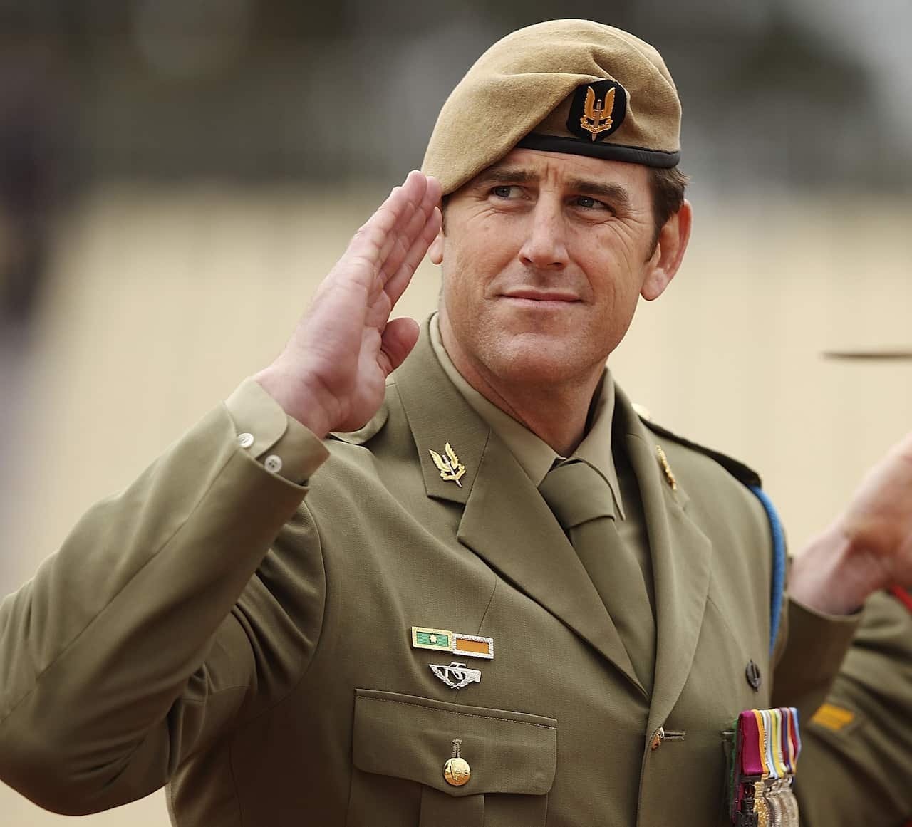 Ben Roberts-smith salutes wearing a green beret and green army dress uniform