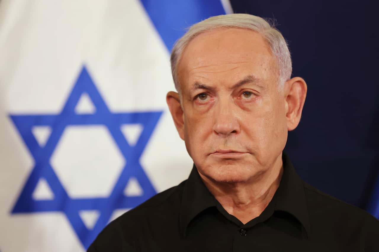 Close up image of a man look ahead with a Star of David out of focus in the background.